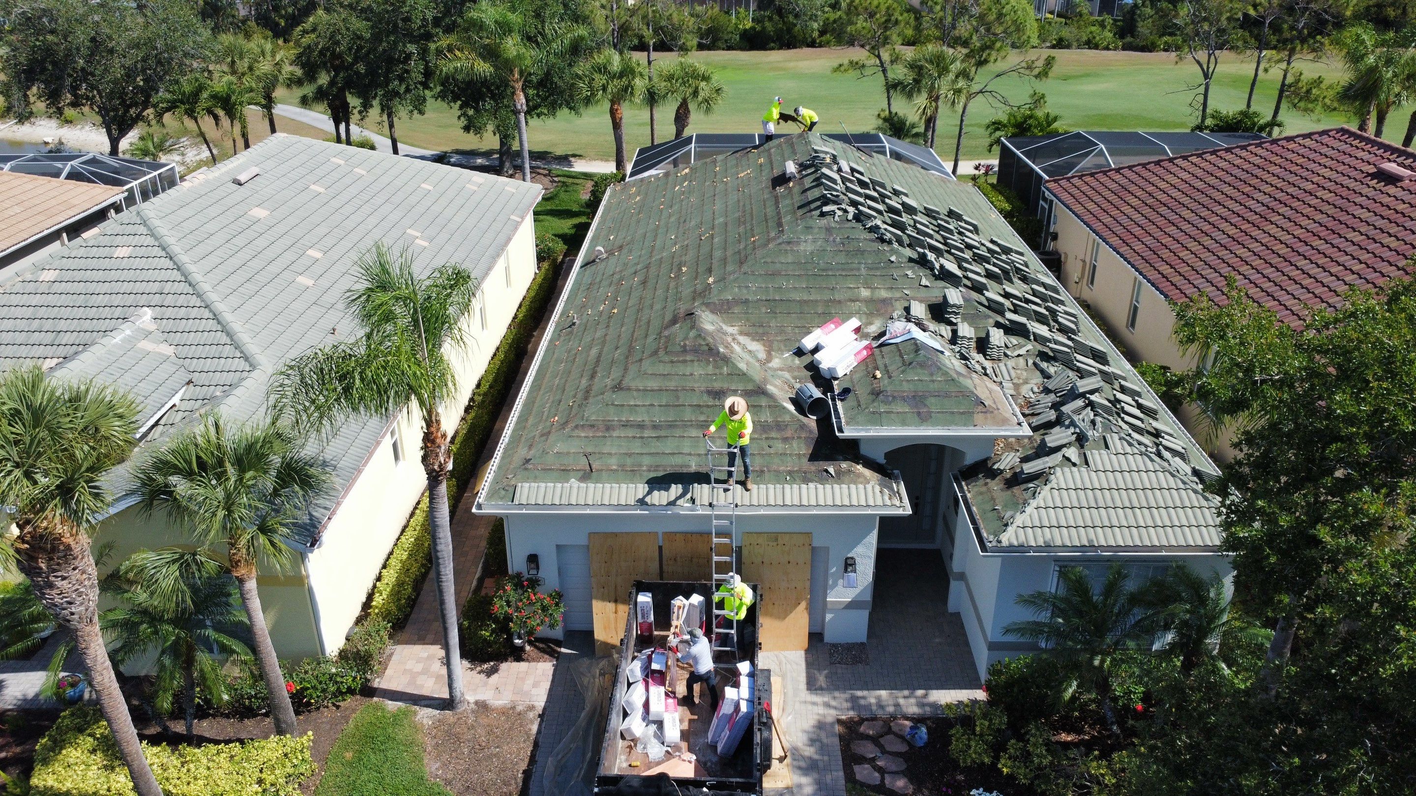 Aerial view of professional roofing team working on house roof repair with safety equipment