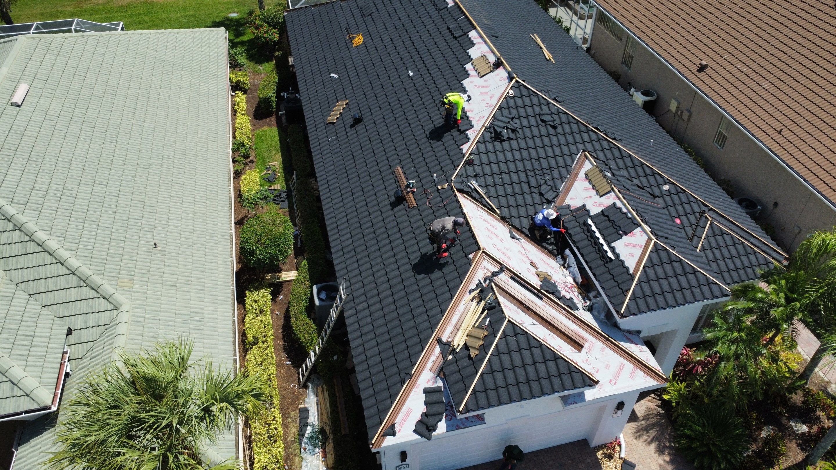 Active roofing construction on luxury estate showing professional work in progress